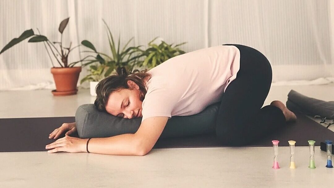 Frau in gehaltener Yin Yoga Position auf Kissen, geeignet für Flugbegleiter ohne Yoga-Erfahrung